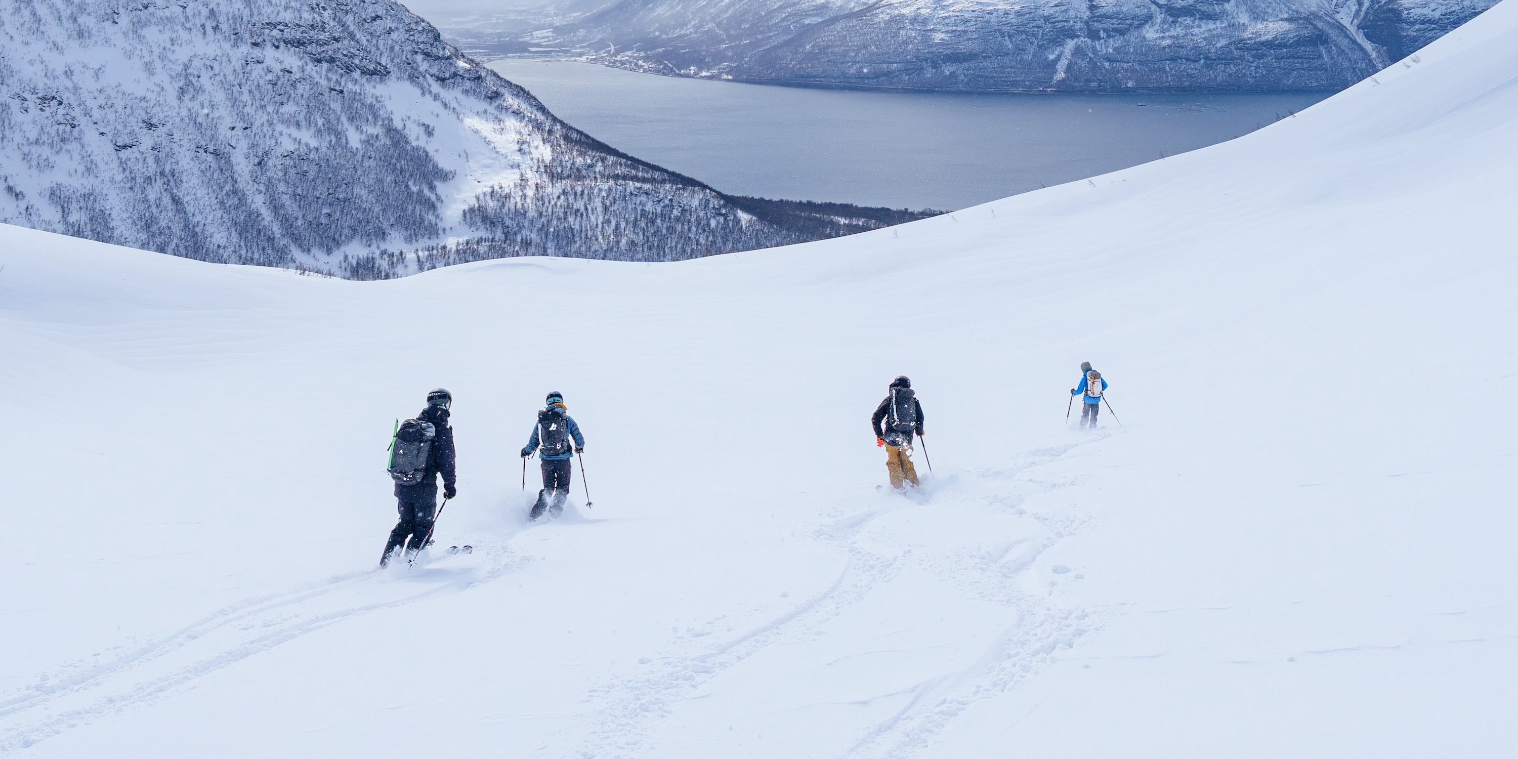Renoun athletes skiing through a powder field in Norway
