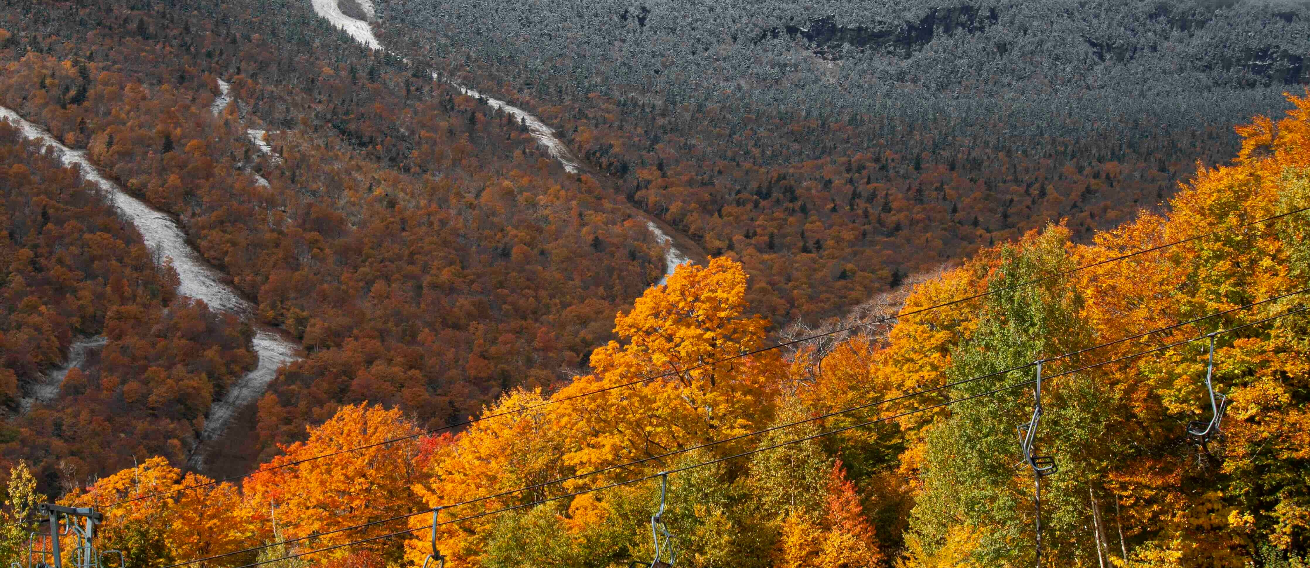 View of Stowe resort with snow on the trails during peak leaf peeping season