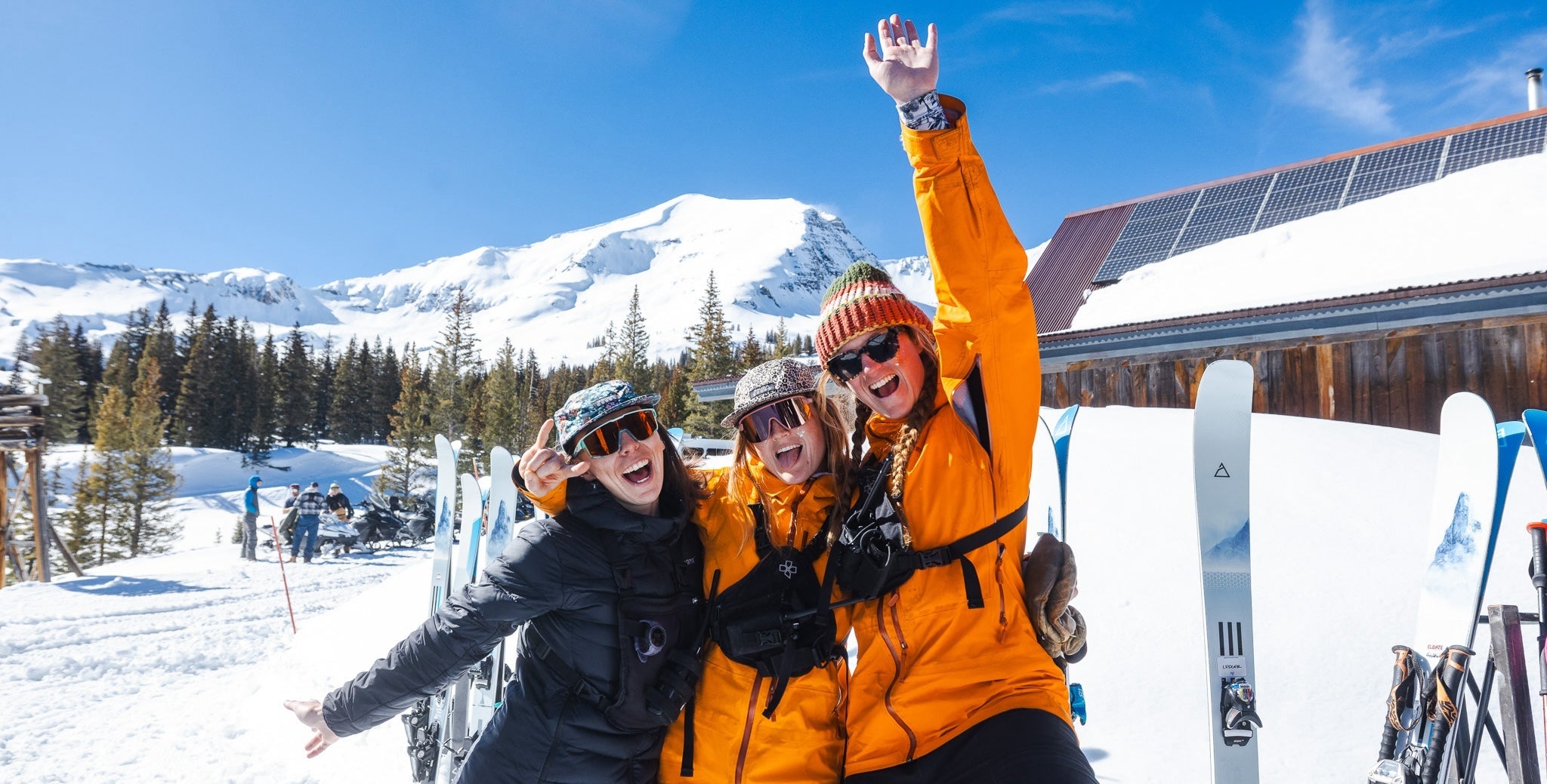 Three women enjoying spring skiing parties in the mountains while surrounded by Renoun skis
