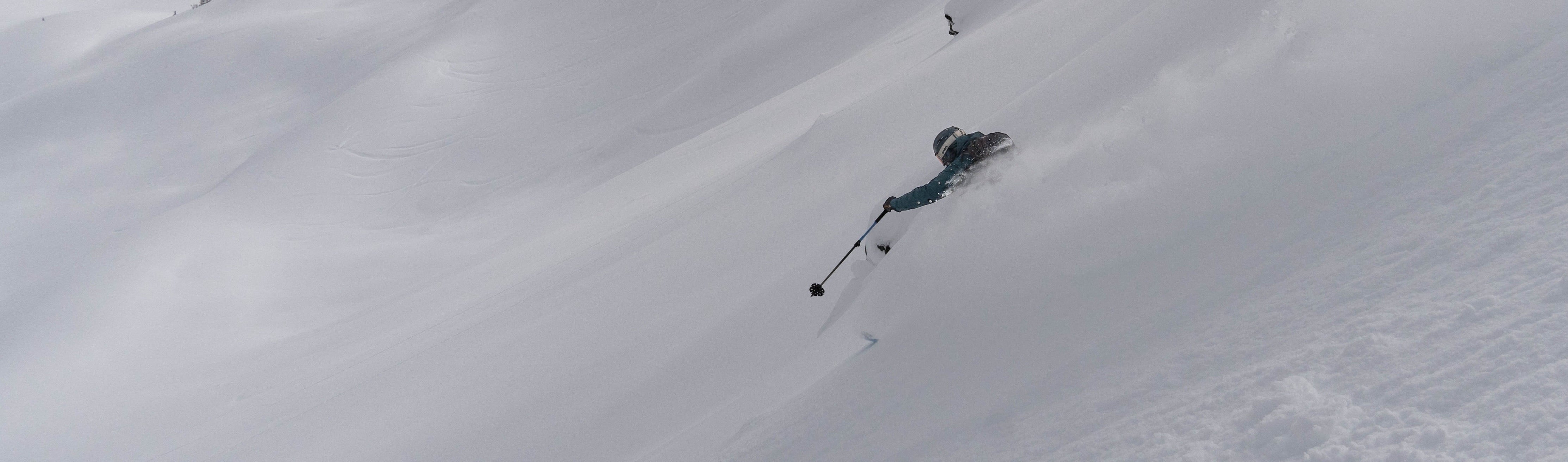 Man skiing on Renoun Citadel downhill skis through a powder field at a ski resort