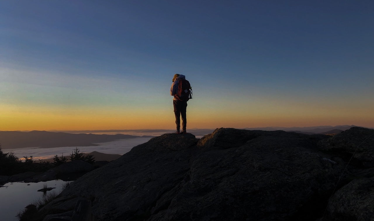 Renoun employee Taegen Yardley hiking on top of Mount Mansfield at sunrise after camping at the summit in Stowe, Vermont.